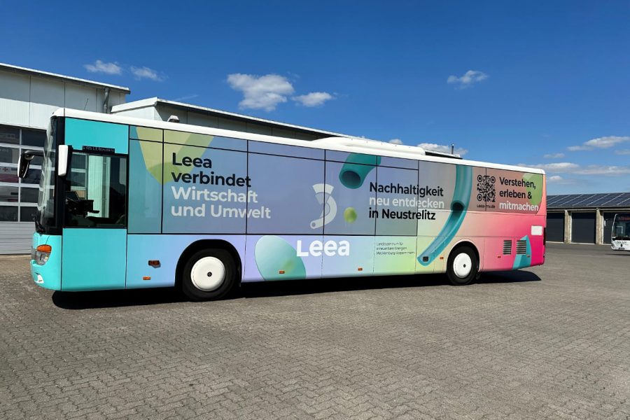 Ein Linienbus steht auf einem Hof und ist mit einer farbenfrohen Werbung für das Landeszentrum für erneuerbare Energien Mecklenburg-Vorpommern beklebt.