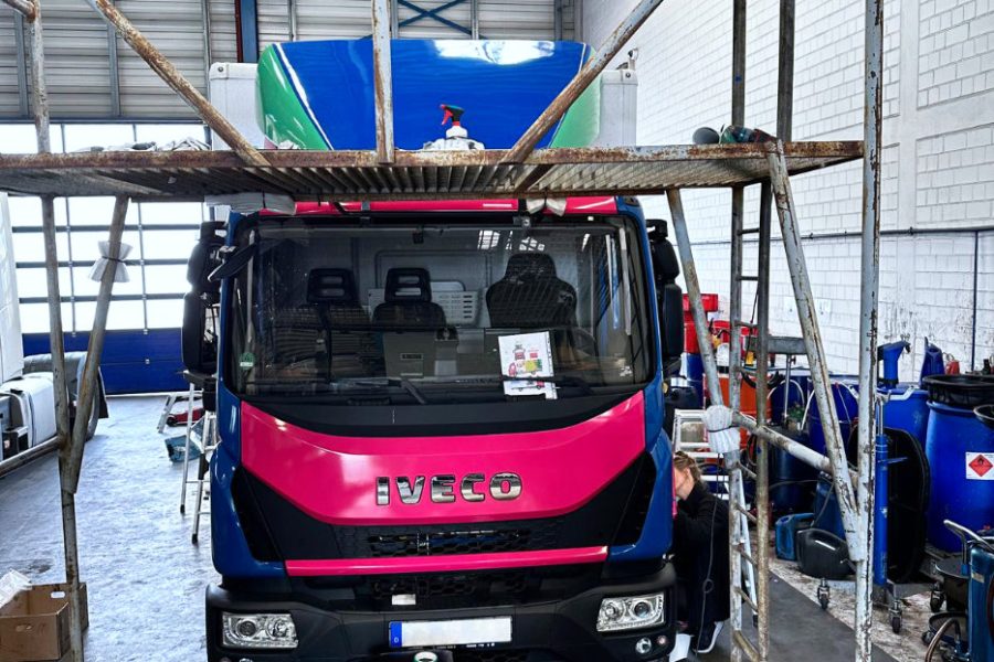 Ein dunkelblauer Iveco-LKW wird in pink neu foliert.